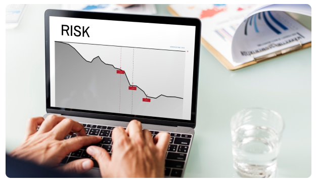 Laptop screen displaying a declining chart labeled 'Risk'